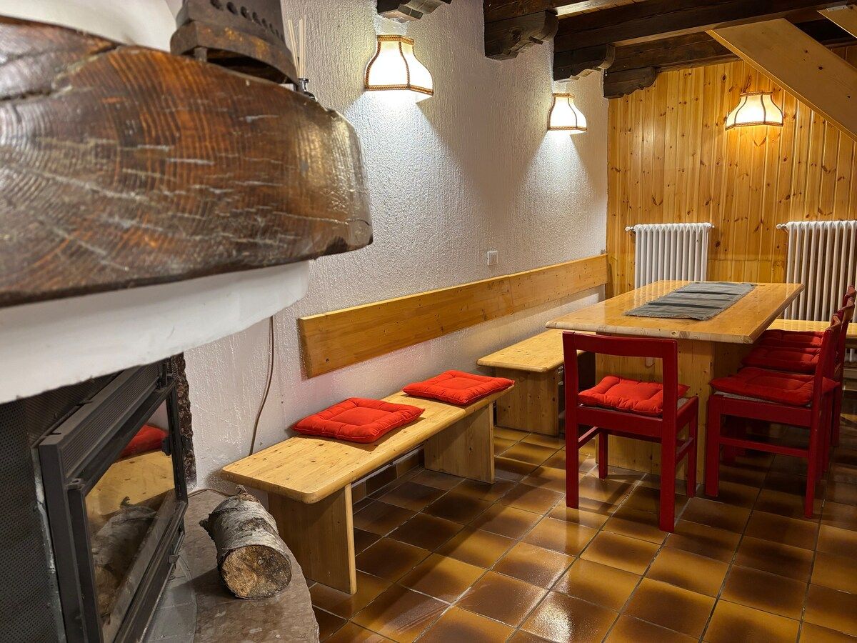 Zona pranzo con panche, tavolo in legno e caminetto